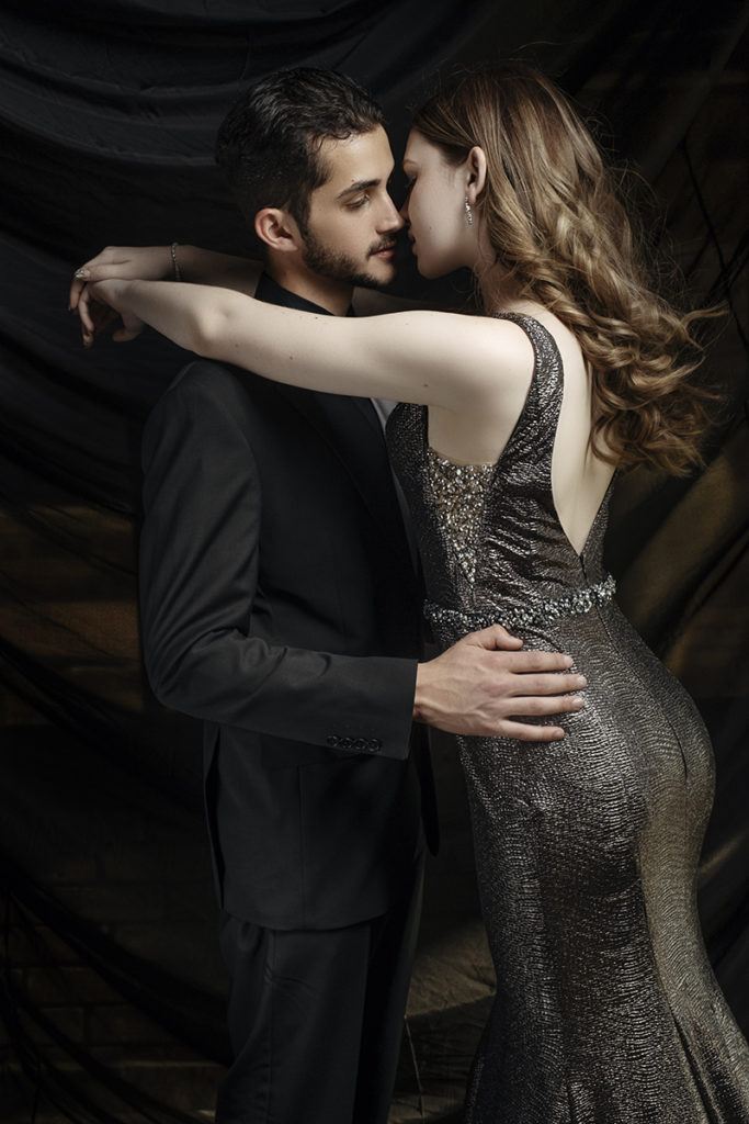 Studio image of couple almost kissing in dark suit and silver dress for her matric dance by Loci Photography