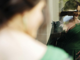 Image of young woman in a green dress reflected in a window during her professional matric dance photoshoot by Loci Photography